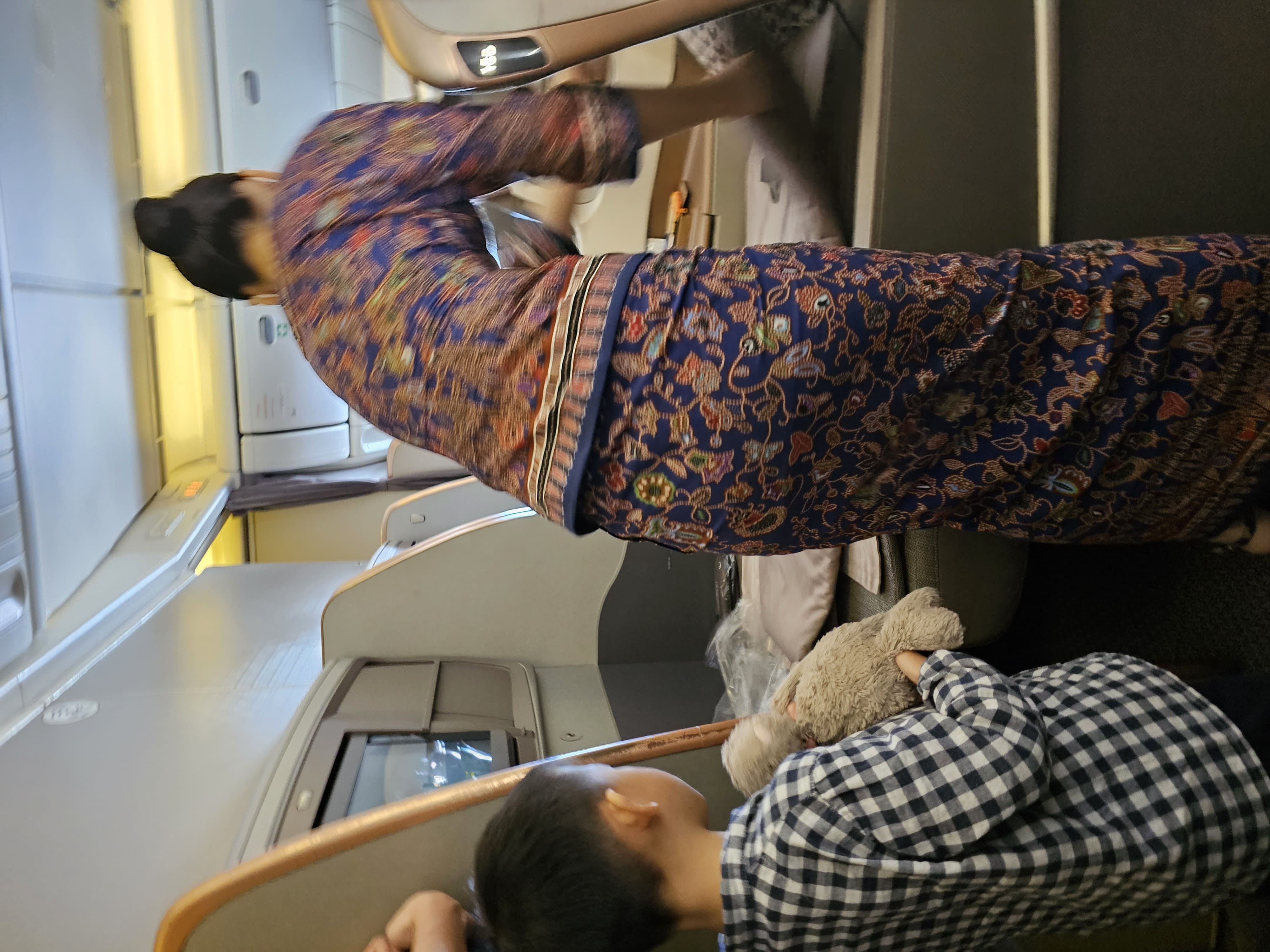 Singapore Airline Stewardess converting the seat to lie flat bed