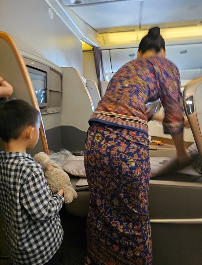 stewardess preparing his bed that can be converted to lie flat